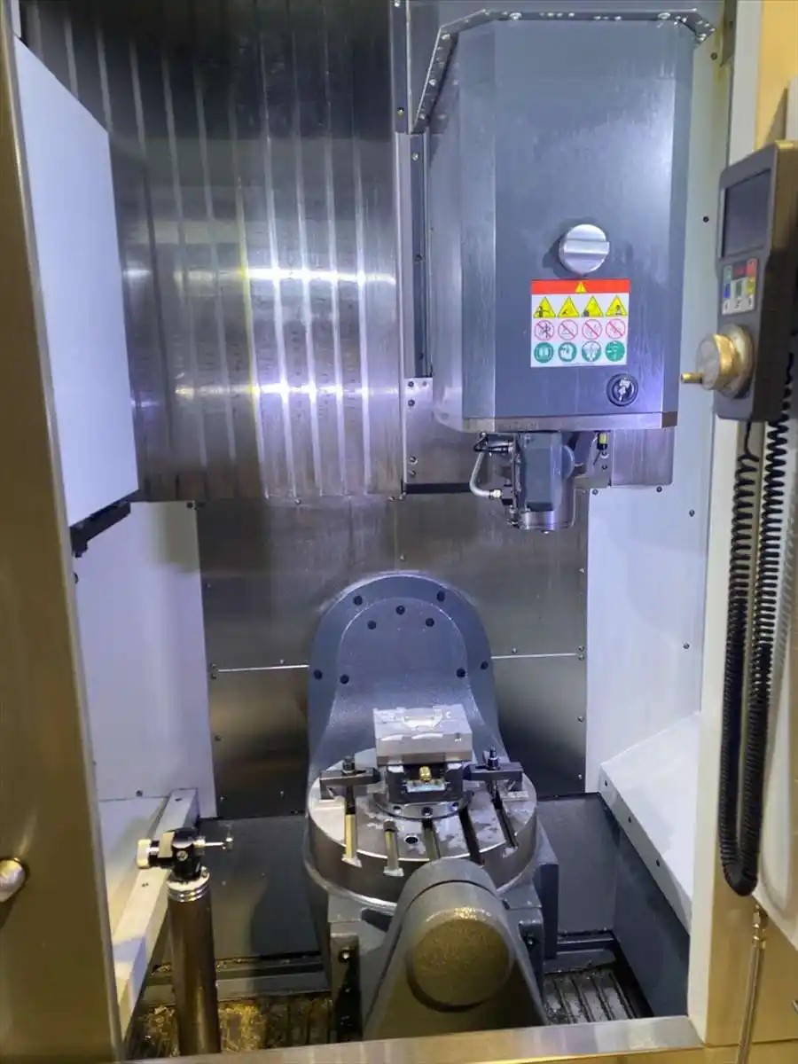 Interior of Haas UMC-500 showing trunnion table, workpiece clamped, and tool-setting probe