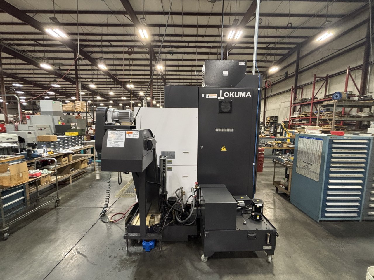 Rear and chip-conveyor side of Okuma MULTUS B250II in a dealer showroom aisle