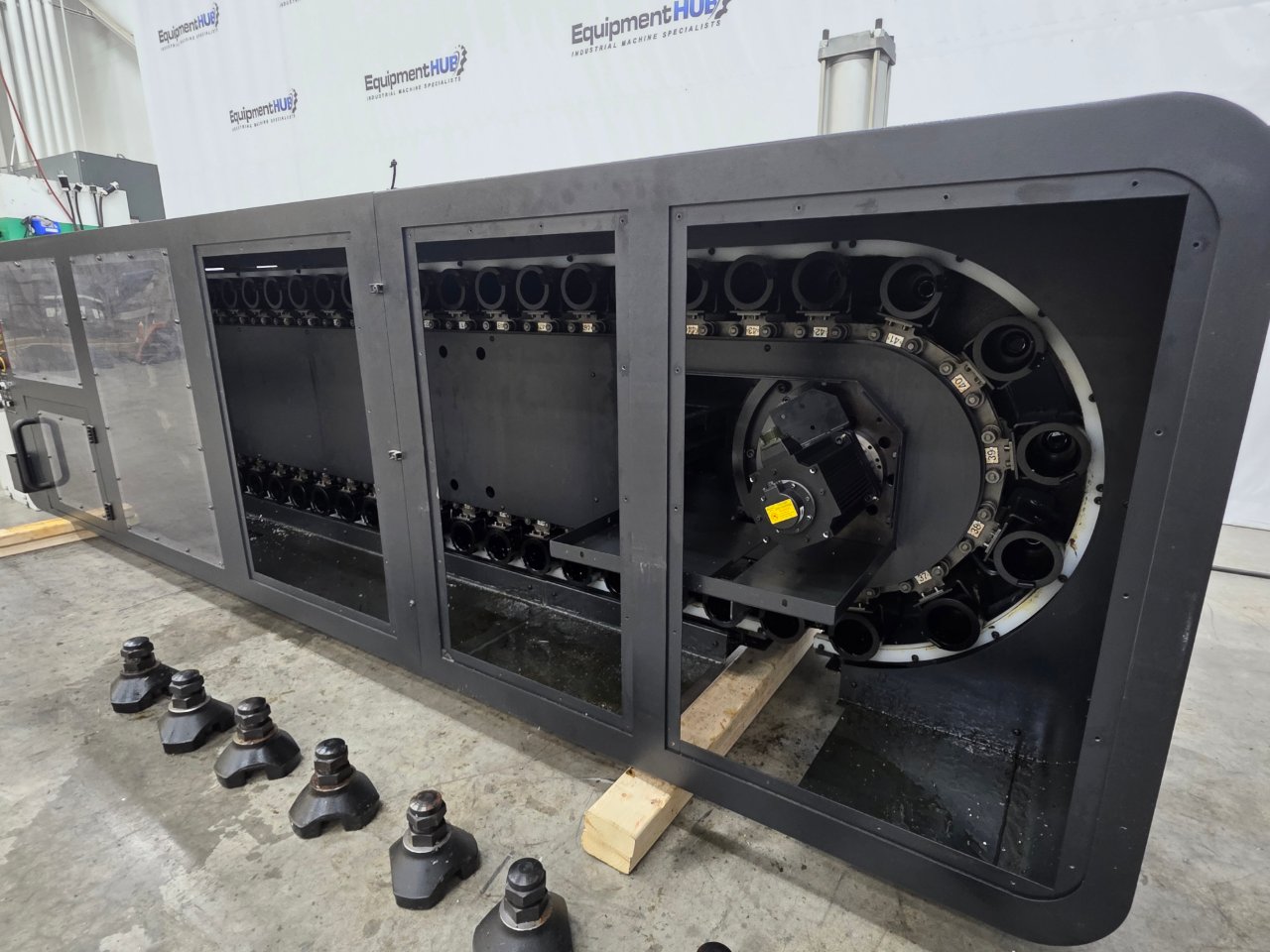 Side-mount chain tool magazine from a DN Solutions MYNX 6500/50 II detached and set on wood blocks, with leveling feet on the floor