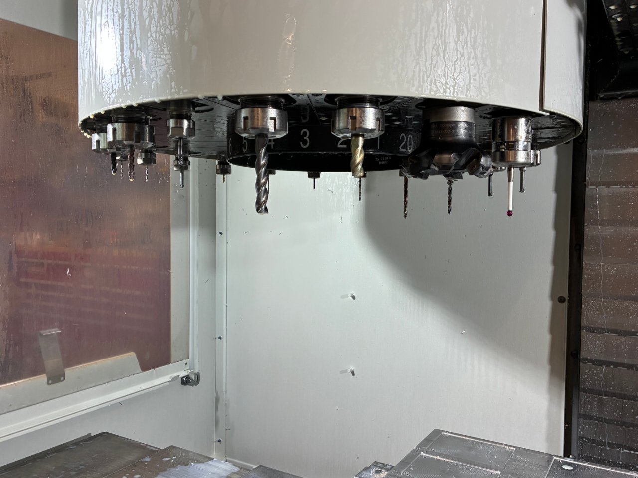 Haas VF-2 carousel tool changer loaded with CAT40 tool holders, end mills, a face mill, and a probe